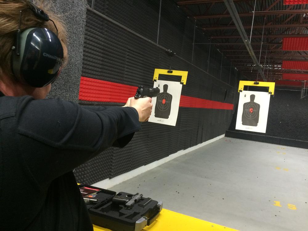 person wearing a black long sleeve shirt shooting a pistol at a paper target