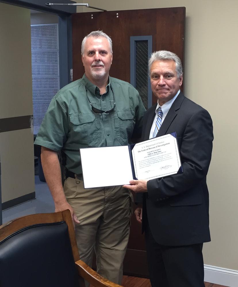 Matt Sims being presented with a certificate of recognition by Bren Tallent of the FBI
