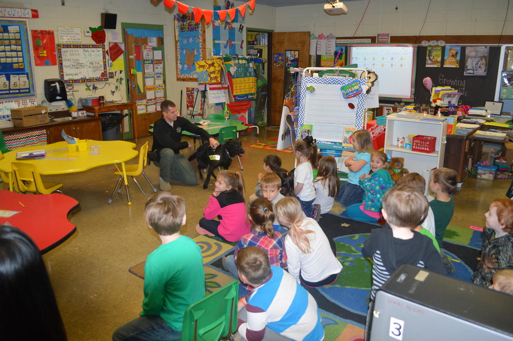 kindergarten students sitting a the floor watching Deputy Michael Green and Keelo