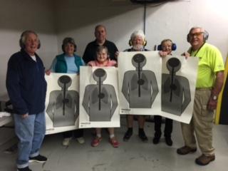 several people holding their paper target after practicing at the firearms range