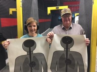 2 people holding their targets from practicing at the firearms range