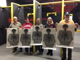 5 people holding their targets from the firearms range