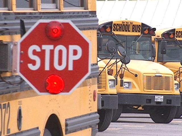 School Bus with red stop sign and 2 buses in the background