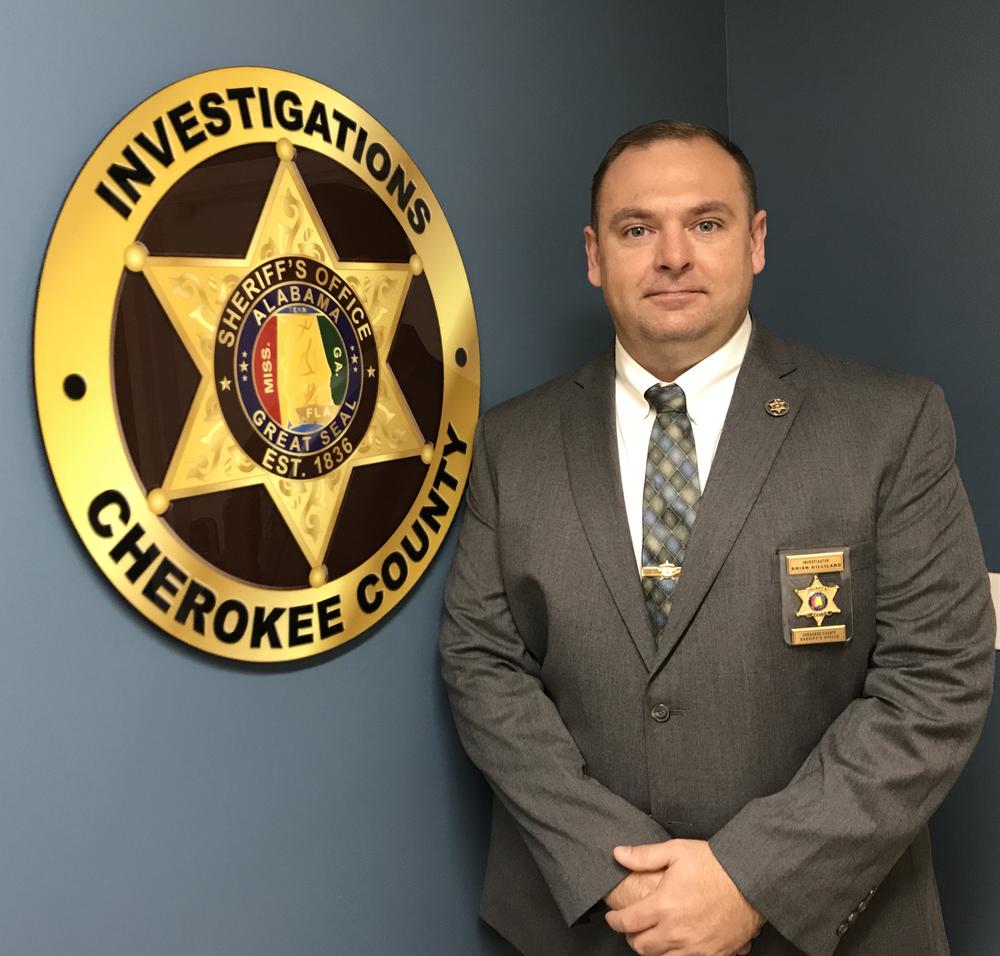 Investigator Brian Gilliland standing next the the Cherokee County Investigations badge