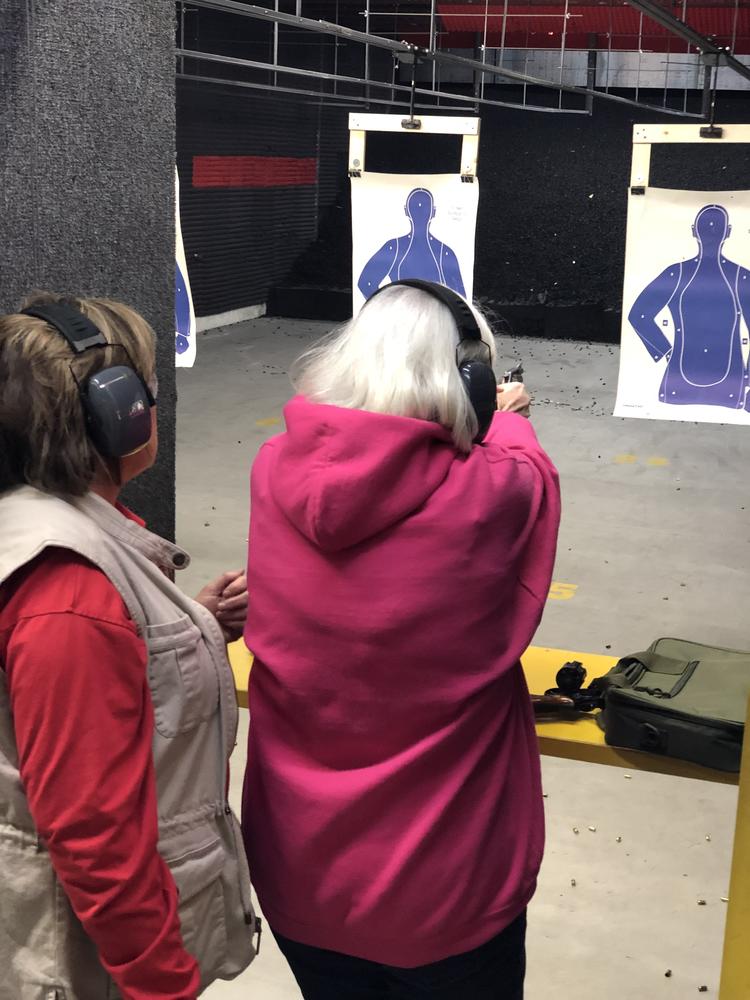 woman being instructed on how to use a firearm