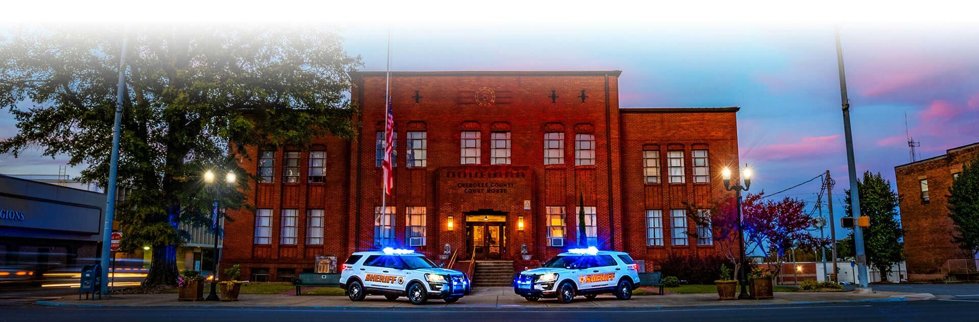 Colorized vehicles before a sunset in front of the sheriffs office.
